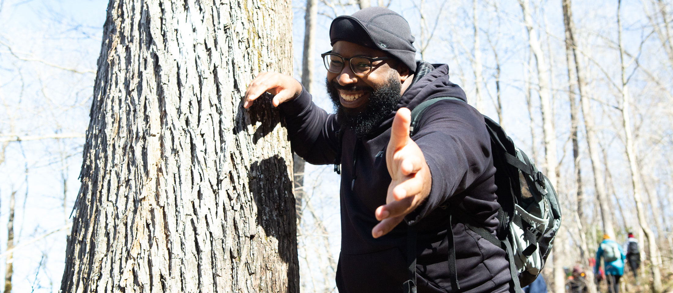 Man leaning against a tree holding out hand. Visit outdoorafro.org